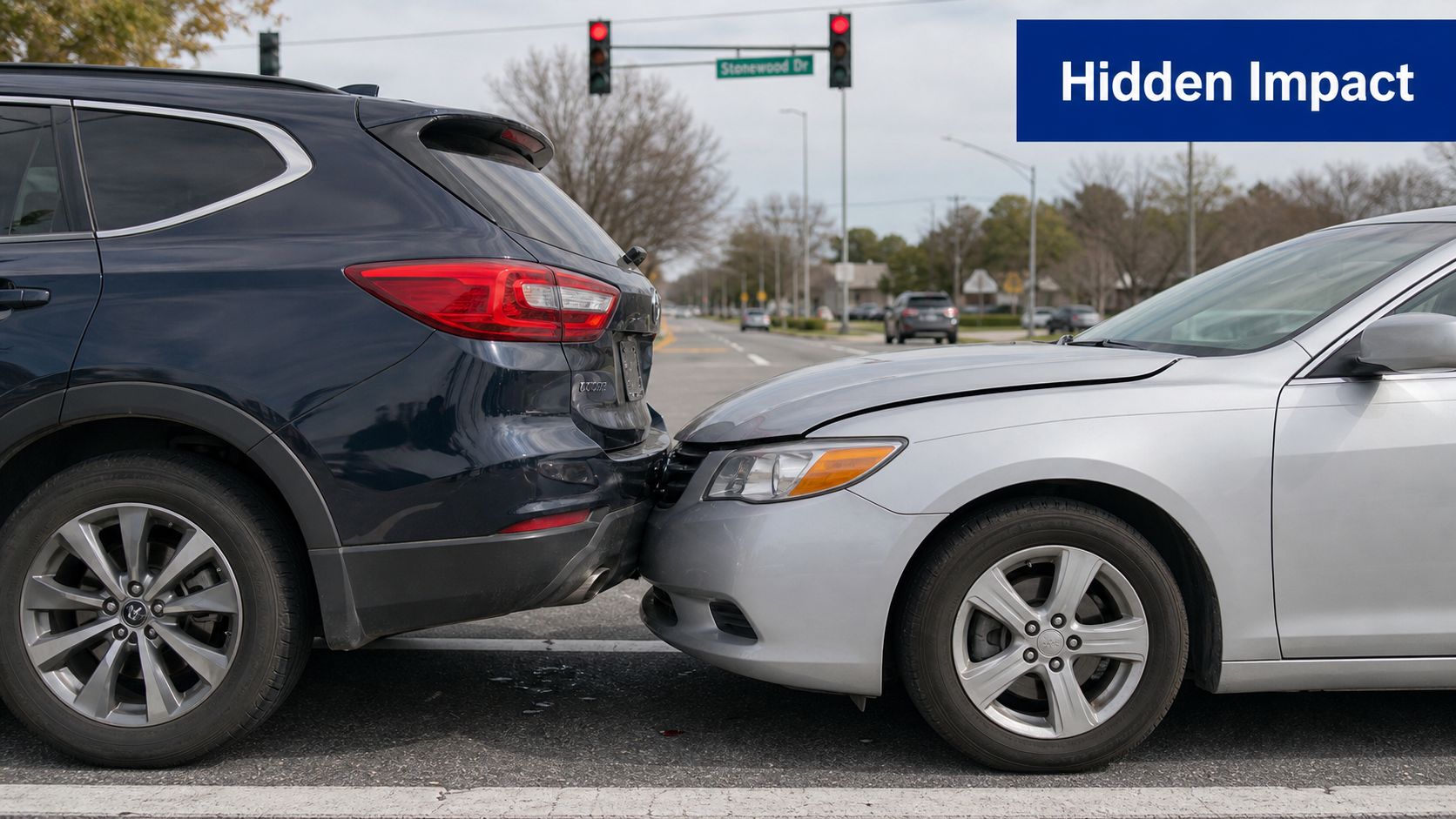 A silver sedan and a dark SUV involved in a rear-end collision at a street intersection.